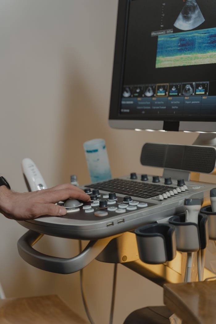 Close-up of a medical practitioner using an ultrasound machine with visible hand and display.