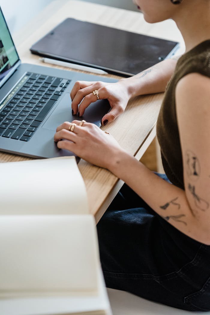 A woman typing on a laptop at a wooden desk in a cozy home setting.