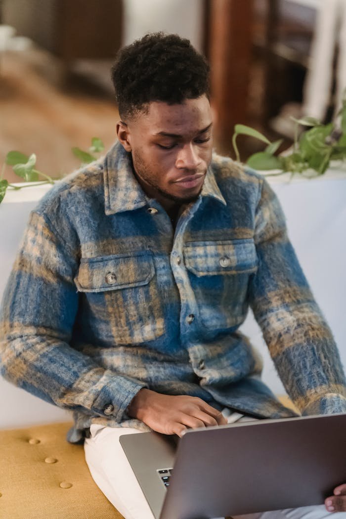 Young man in a casual setting intensely focused on his laptop, indoors.